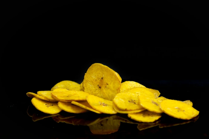 A pile of crispy banana chips on black background